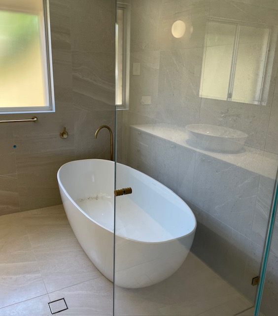 Freestanding bath behind frameless glass